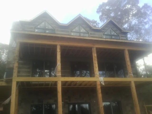 Dormers and porch framing on a large log home under construction — Roof Coating work by our crew in Sunderland