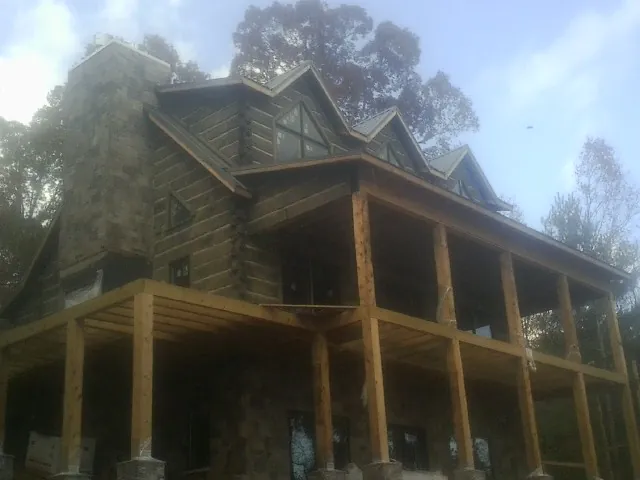 Stone chimney and dormers on a large log home with a timber porch in Sunderland