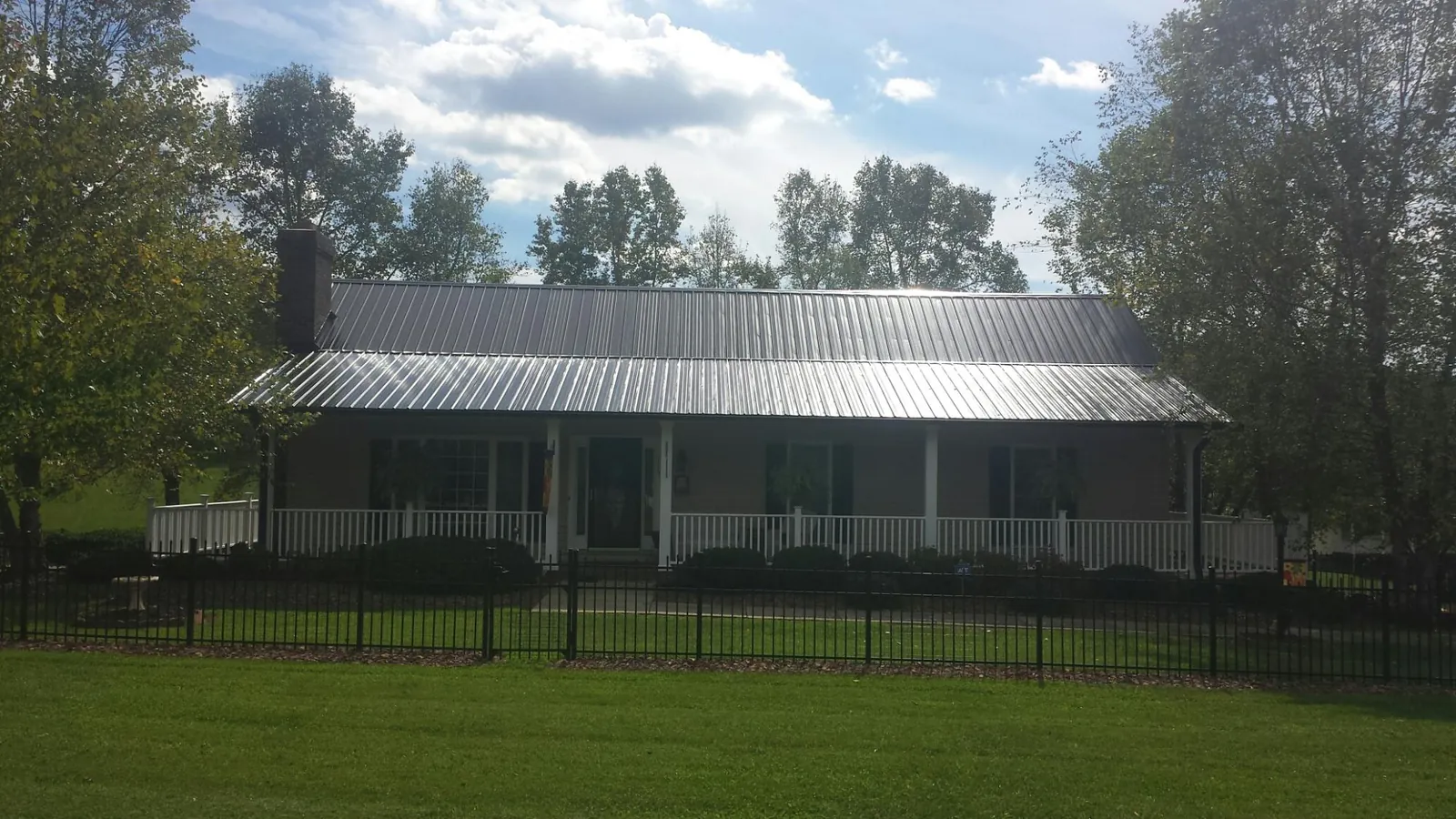 Gray metal roof on a brick ranch with a full width front porch — Gutter Guard Installation work by our crew in Sunderland