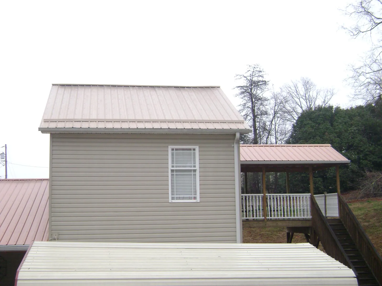 Tan metal roofs on a two story addition and attached porch, from a Roof Replacement job in Sunderland