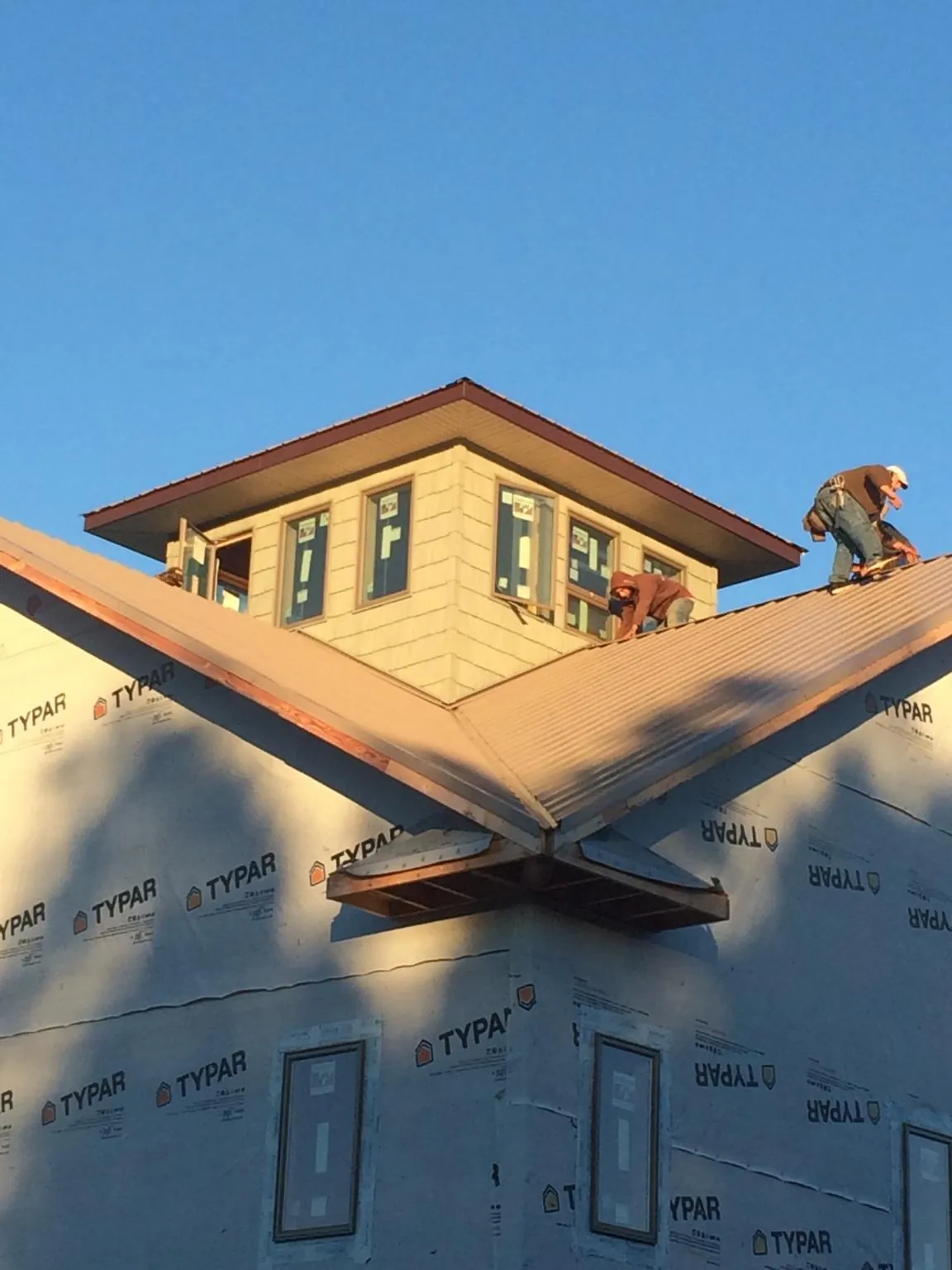 Roofers working around a rooftop cupola on a new metal roof at sunset — Roof Waterproofing in Sunderland by Roofing Brothers